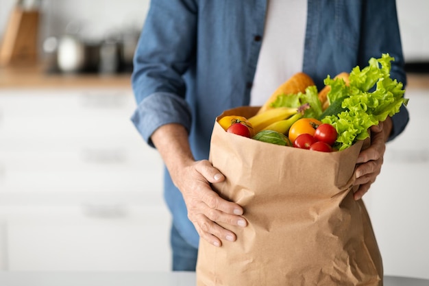 Market delivery concept unrecognizable man holding paper bag with groceries in kitchen