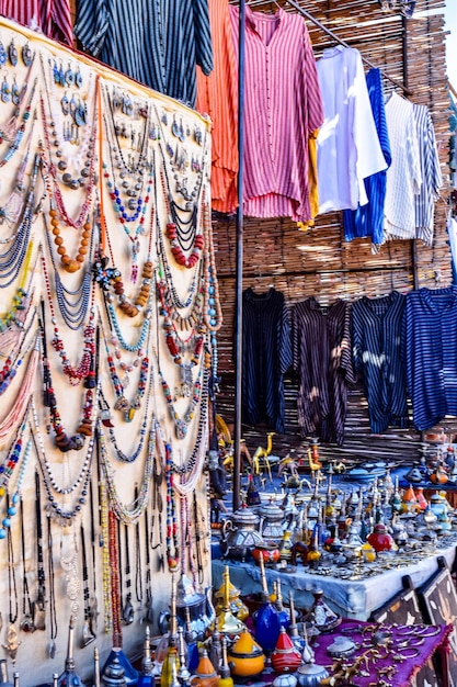 A market with a lot of clothes hanging from the ceiling and jewellery