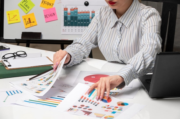 Marketing business lady in grey blazer in office with computer close up looking for a paper