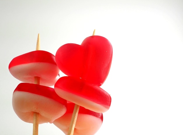 Marmalade hearts pierced with wooden skewers on a white background