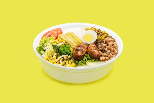 Marmita or marmitex Brazilian homedelivered lunch meal with rice sausage farofa and salad beans copy space yellow background