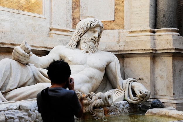 Marphurius or Marforio talking statues of Rome with an asian visitor taking a photo Rome Italy