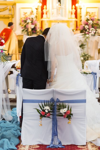 Married couple seen from back in cathedral during the wedding ceremony