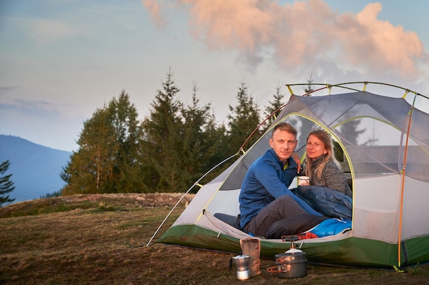 Married pair of campers relaxing in tent outdoors