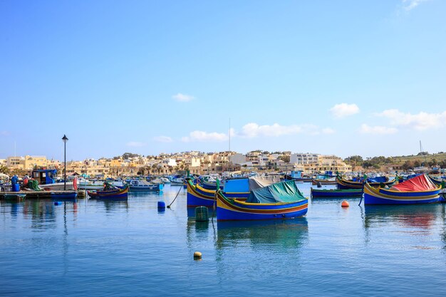 Marsaxlokk historic harbor full of wooden boats in Malta Blue sky and village background