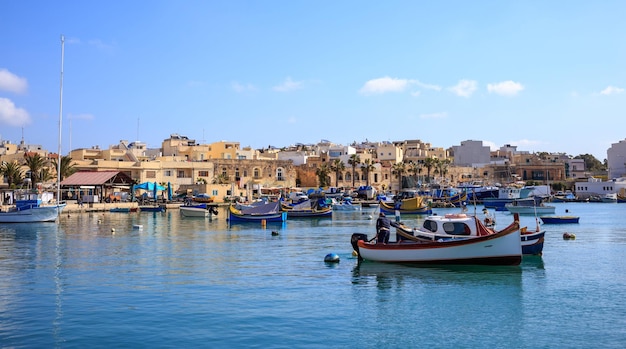 Marsaxlokk historic port full of boats in Malta Blue sky and village background