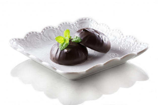 Marshmallow in chocolate and a mint leaf isolated on a white background