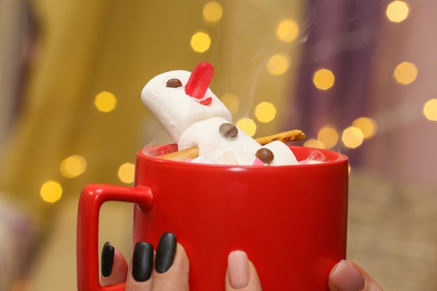 Marshmallow snowman in hot chocolate in a red cup