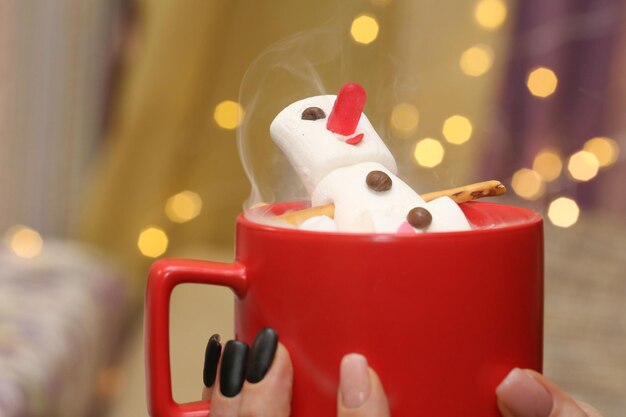 Marshmallow snowman in hot chocolate in a red cup