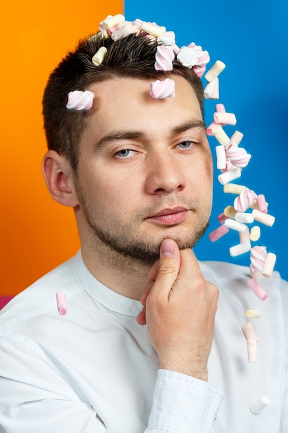 Marshmallows sprinkle on the man’s head. Bright man portrait with sweets on his hair