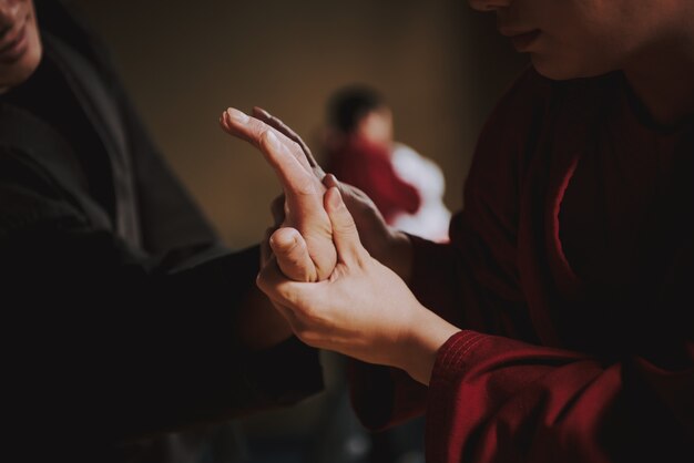 Martial arts student in red blocking hand of sensei