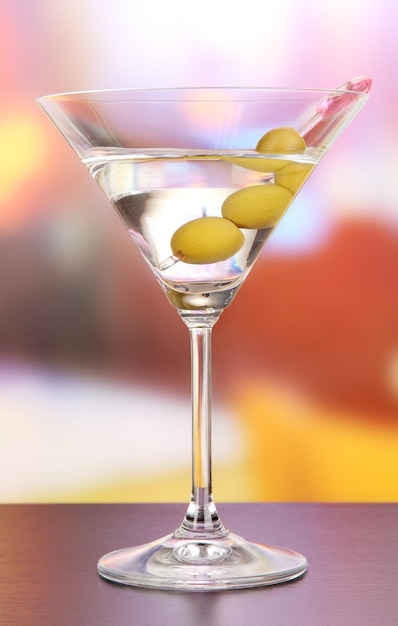 Martini with green olives on table in bar