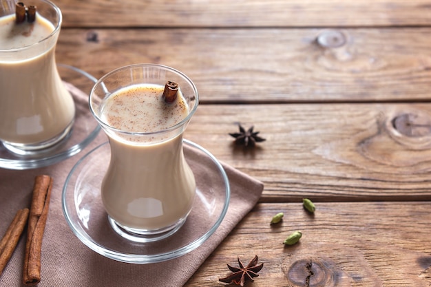 Masala chai with cinnamon in transparent glasses on a wooden table.