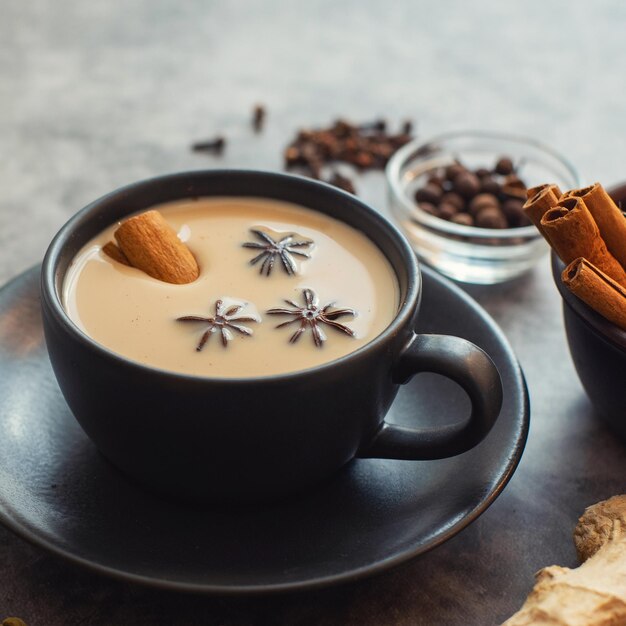 Masala tea Traditional indian chai in black cup with spiced on grey background