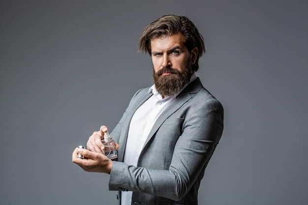 Masculine perfume bearded man in a suit Male holding up bottle of perfume Man perfume fragrance Perfume or cologne bottle and perfumery cosmetics scent cologne bottle male holding cologne