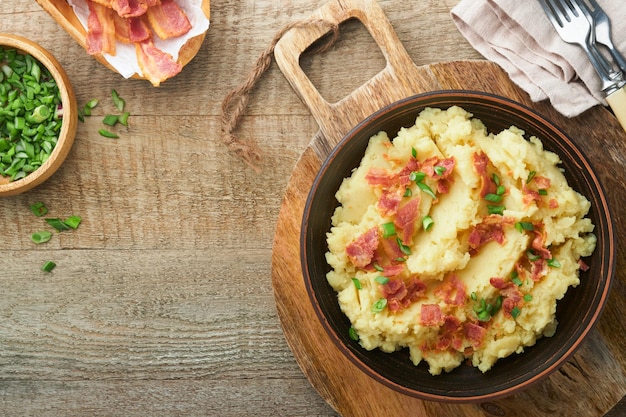 Mashed potatoes Bacon mashed potatoes with green onion pepper and cheddar cheese in bowl on old wooden backgrounds Delicious creamy mashed potatoes Top view