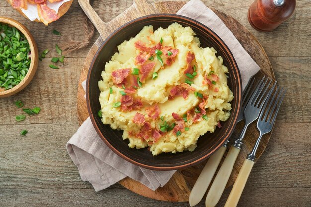 Mashed potatoes Bacon mashed potatoes with green onion pepper and cheddar cheese in bowl on old wooden backgrounds Delicious creamy mashed potatoes Top view