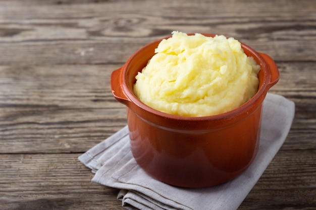 Mashed potatoes in a clay pot, vintage wood background