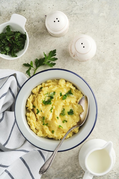 Mashed potatoes Hot mashed potatoes with butter fresh parsley herbs and pepper in bowl on slate stone or concrete backgrounds Delicious creamy mashed potatoes Top view