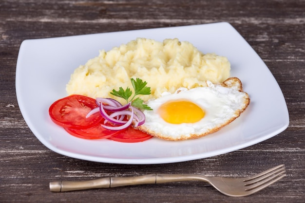 Mashed potatoes with fried eggs and tomato