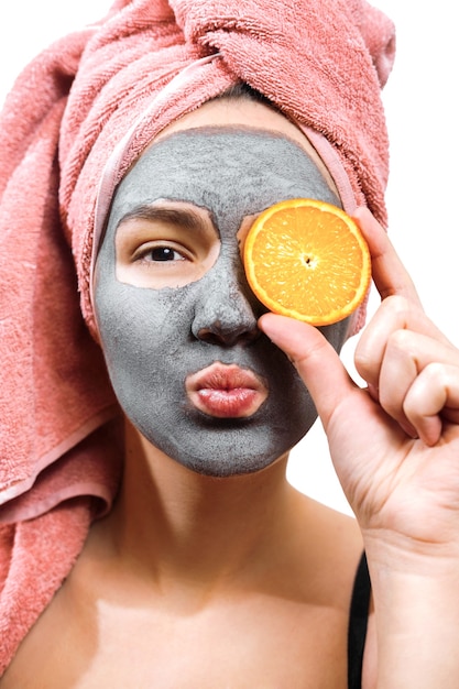 Mask for skin woman, happy and funny girl makes a mask for face skin, girl closes her eyes with orange and send an air kiss in the camera, isolated photo