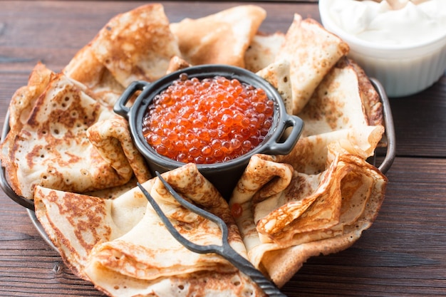 Maslenitsa holiday pancakes with red caviar and sour cream on the table The Russian tradition