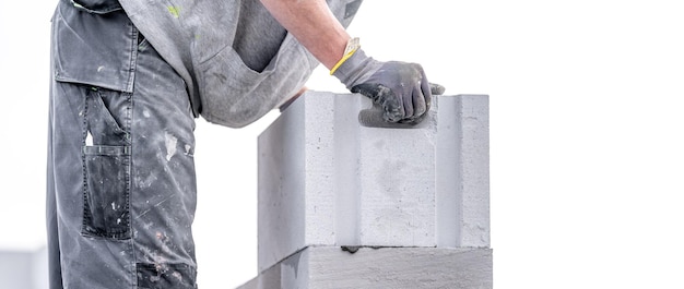 A mason builds the wall of a building from concrete bricks and blocks