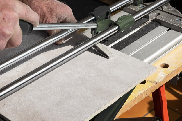 The mason cuts a ceramic tile with a tile cutter