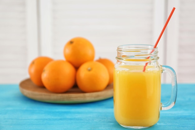 Mason jar with fresh orange juice on table