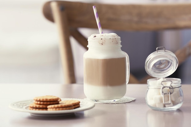 Mason jar with latte macchiato on table indoors