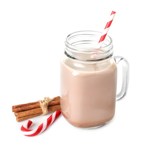 Mason jar of yummy cocoa drink with Christmas candies and cinnamon on white background