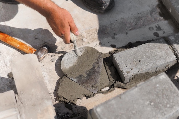 Mason lays out brickwork from gray bricks Hands of builder with trowel closeup Man works at construction site Background