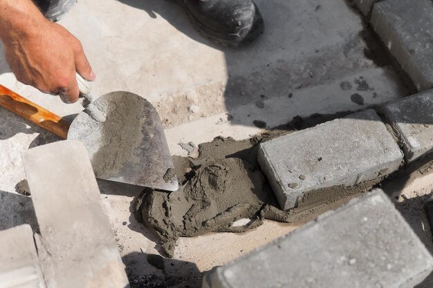 Mason lays out brickwork from gray bricks Hands of builder with trowel closeup Man works at construction site Background