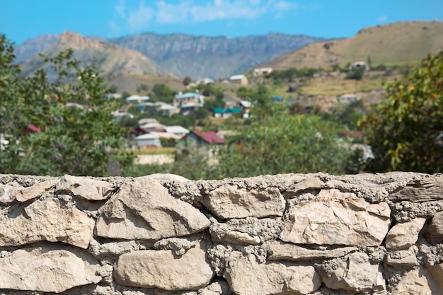 Masonry stone walls of natural foreground with background of a mountain village with houses and trees in defocus Tourism ecology ecofriendly theme