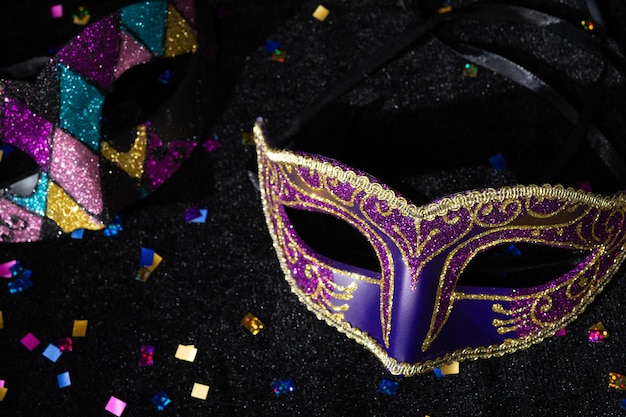 Masquerade mask with confetties on black background