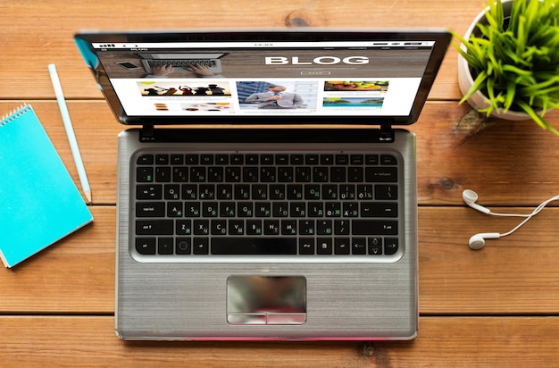 mass media, internet, business and technology concept - close up of laptop computer with blog web page on screen on wooden table