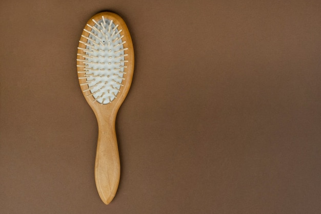 Massage comb with wooden handle on table. Device for combing hair. Eco beauty concept.