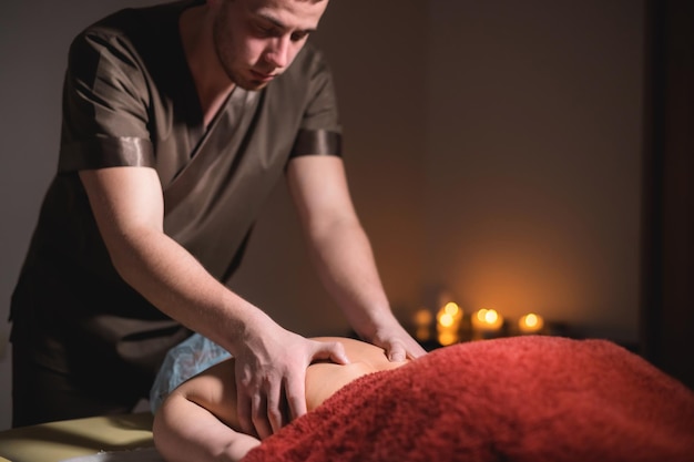 Photo massage of a female back in a dark room of a spa salon male masseur doing massage