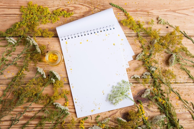 Massage oil in a glass bottle herbs and notepad on wooden table