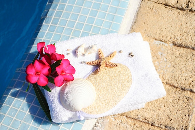 Massage oil shellfish and white towel beside a pool