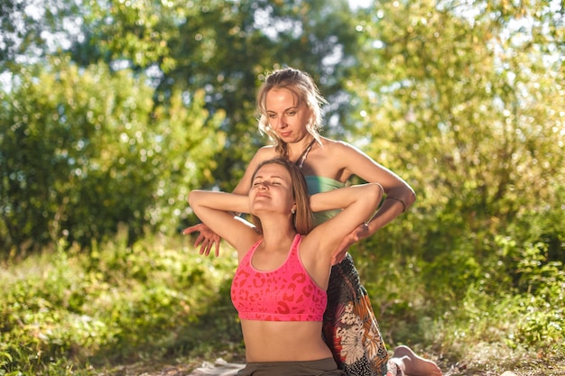 Massage session. Massage trainer gives her client a refreshing massage on the grass.