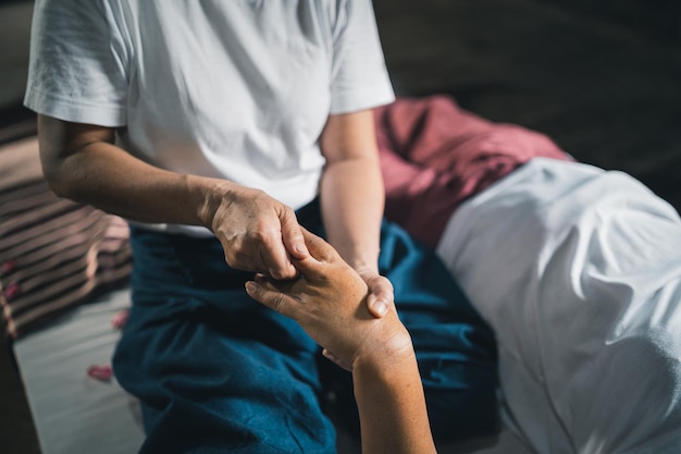 Massage and spa relaxing treatment of office syndrome traditional thai massage style Asain senior female masseuse doing massage treat hand back pain arm pain foot and stress for old woman tired