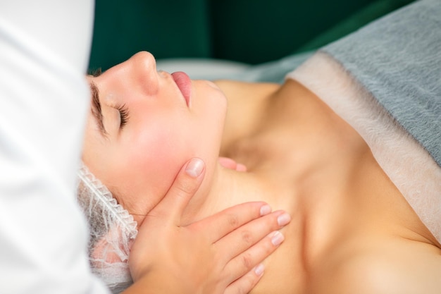 Massaging female neck. Young caucasian woman receiving neck massage relaxing in spa salon.