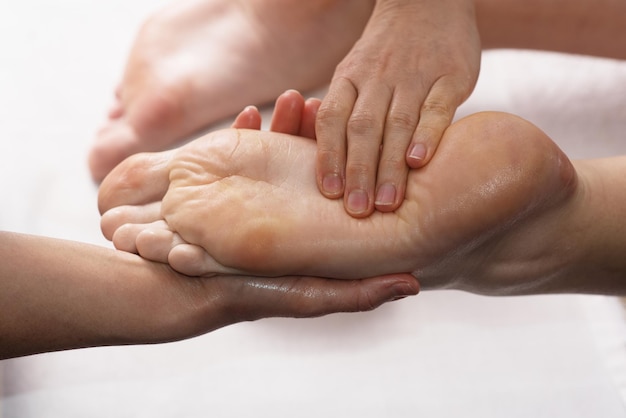 Masseur doing foot massage with oil in spa salon Spa procedures Body care concept Closeup view