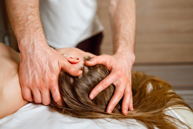 Masseur doing massage on woman's neck and head at the spa