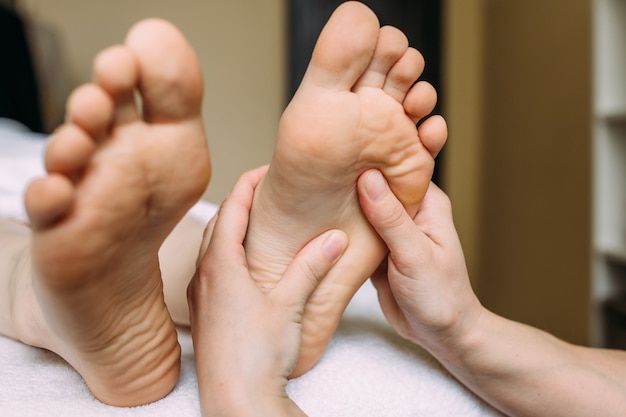 The masseur gives a massage to the female feet at the spa