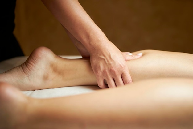 The masseur makes an anticellulite leg massage to a woman anticellulite foot massage