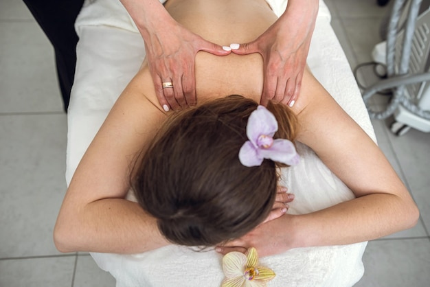 Masseuse hands working massaging back in young beautiful woman client in the spa salon