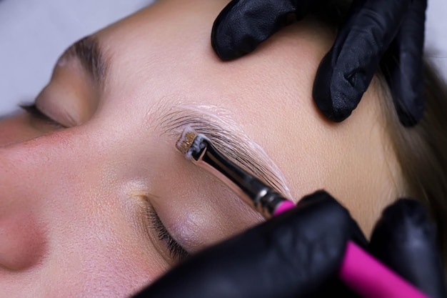 The master applies the compositions on the eyebrows with a brush for laminating the eyebrows