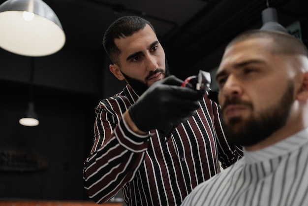 Photo the master barber of caucasian appearance does his job cuts the client's hair with a brutal